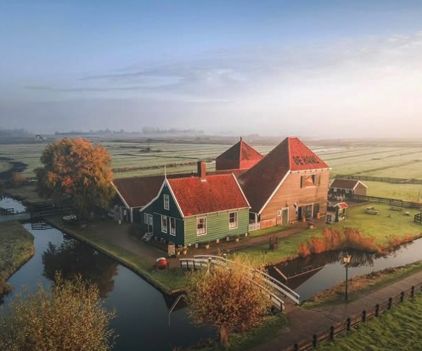 A red-roofed Zaan farmhouse standing alone on the polder at first light