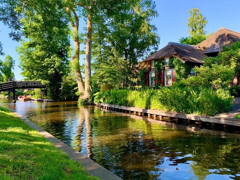 A quiet green canal at Giethoorn with cottages set back among the trees