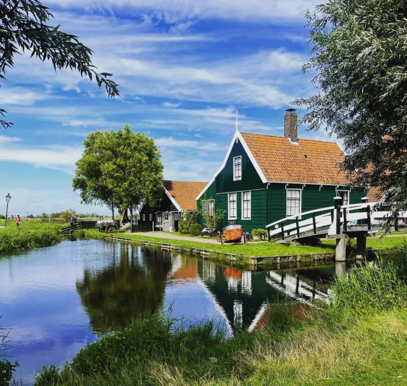 Green Zaan timber houses along the River Zaan with a boat passing in front of them