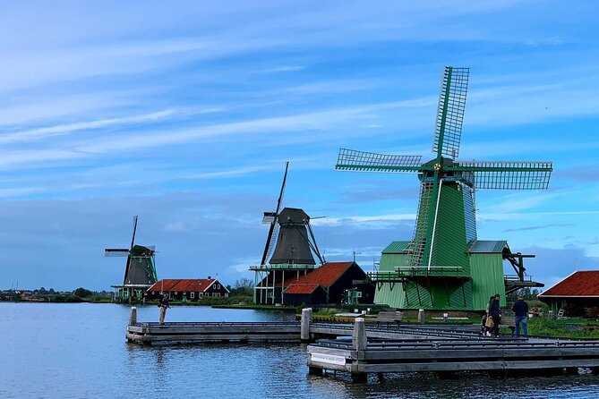 Zaanse Schans windmills lined along the waterfront under scattered cloud